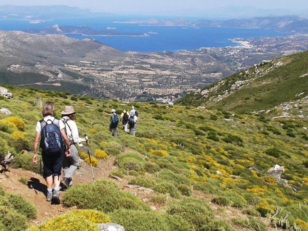 Wandelaars op bergpad op Evia, Griekenland, met uitzicht op de kust en dorpen tijdens een wandelvakantie.