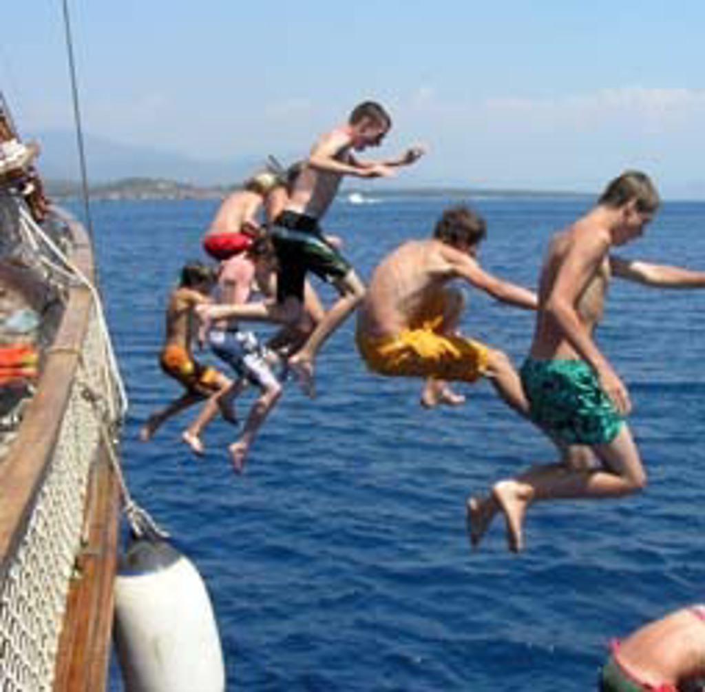 Kinderen springen vanaf een boot de zee in tijdens een familiereis in Zuid-Turkije.