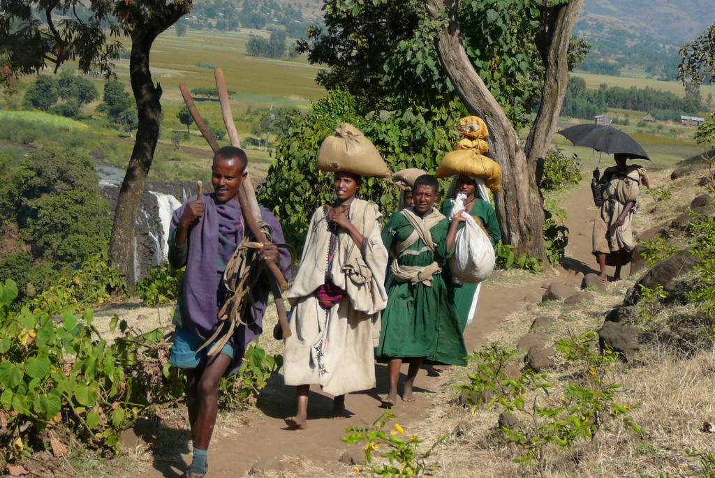 Lokale bewoners wandelen over een landweg in Ethiopië met bagage op het hoofd, tijdens een groepsrondreis.