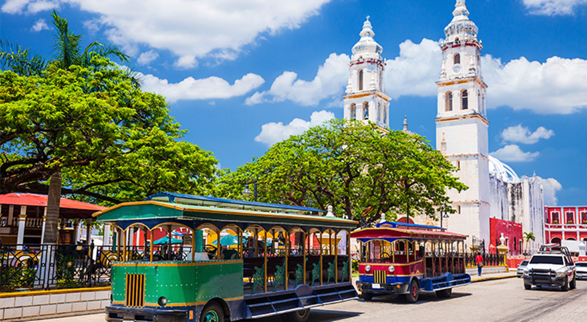 Campeche Toeristentreintjes op straat bij witte kathedraal met twee torens onder blauwe lucht.