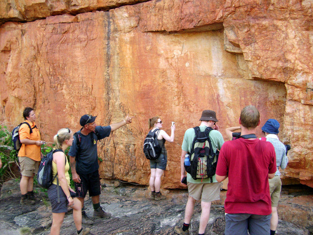 Groepsrondreis West-Australië: reizigers bekijken rotstekeningen op een rotswand tijdens een wandeling.