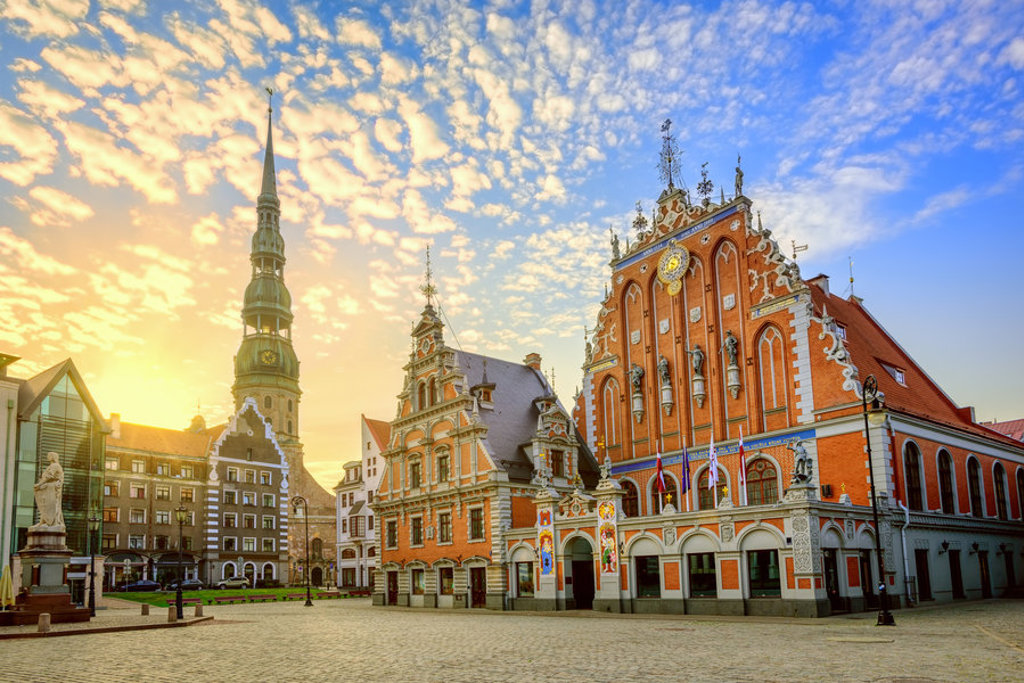 Stadhuisplein in Riga met het Huis van de Zwarthoofden en de Sint-Pieterskerk bij zonsondergang.