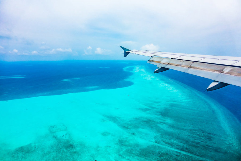 Vliegtuigvleugel boven het turkooizen water bij Zanzibar tijdens familiereis Kenia, Tanzania & Zanzibar.