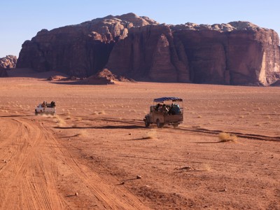 Jeepsafari door de Wadi Rum-woestijn in Jordanië, met rode zandvlakte en hoge rotsformaties.