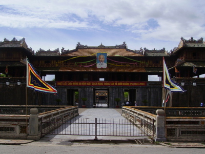 Keizerlijke stadspoort in Hué op de Route Vietnam, met brug en kleurrijke vlaggen.