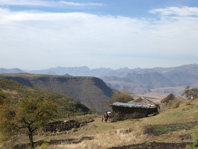 Uitzicht op berglandschap in Lesotho met traditionele ronde huisjes en wandelaarspad.
