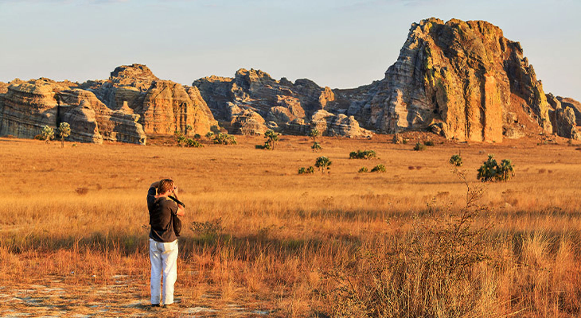 Isalo Nationaal Park Fotograaf in savanne met rotsformaties en bergmassief bij zonsondergang.