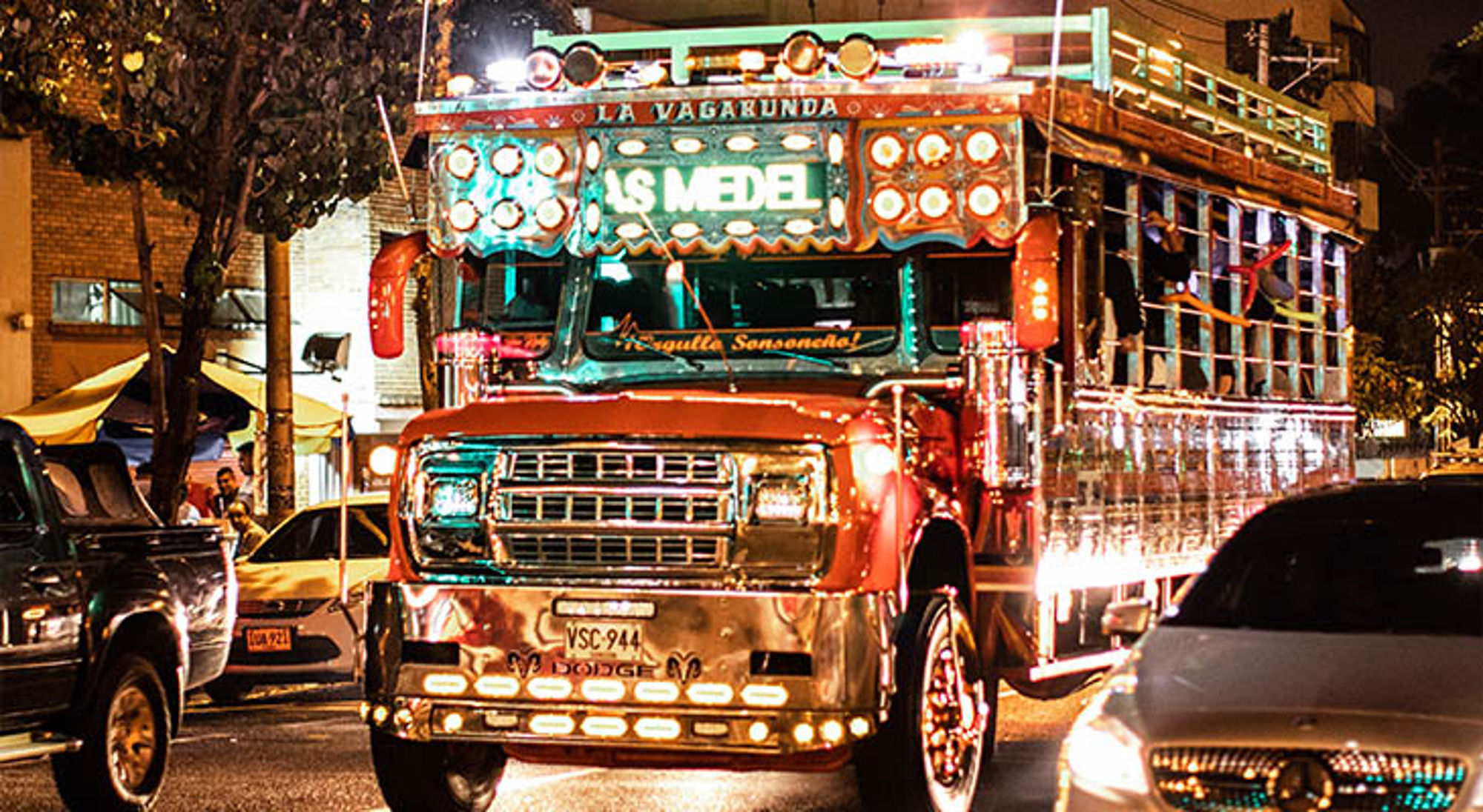 Feestbus in Cartagena Kleurrijke chiva-bus met felle verlichting in het nachtverkeer.