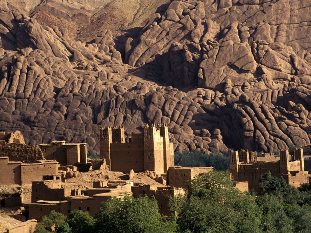 Kasbah in Marokko met lemen gebouwen aan de voet van een rotsachtig bergmassief.