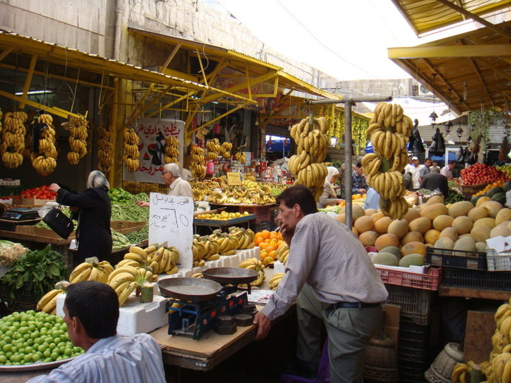 Drukke markt in Jordanië met kraampjes vol bananen en vers fruit tijdens de groepsrondreis Jordanië Hoogtepunten.