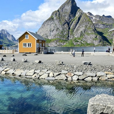 Kleurrijke vissershuisjes aan een fjord met bergen op de achtergrond, tijdens een groepsrondreis Noorwegen.