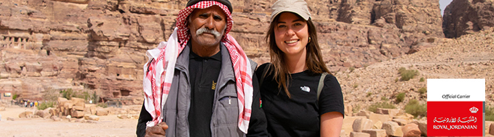 Reiziger met lokale gids in Petra, Jordanië, met rotswanden op de achtergrond.