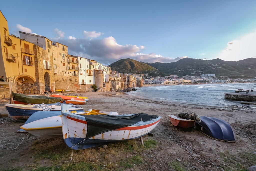Vissersbootjes op het strand bij kleurrijke huizen aan de kust van Sicilië, Zuid-Italië.