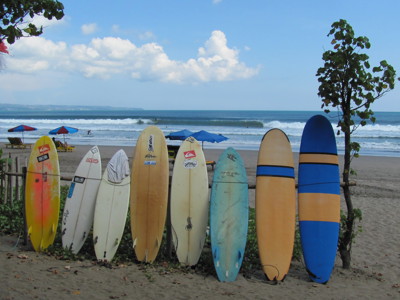 Surfplanken op het strand van Bali met golven op de achtergrond.