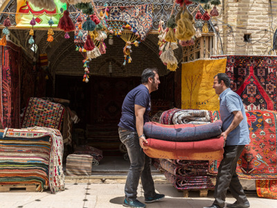 Tapijthandelaren dragen opgerolde Perzische tapijten in een bazaar in Iran.