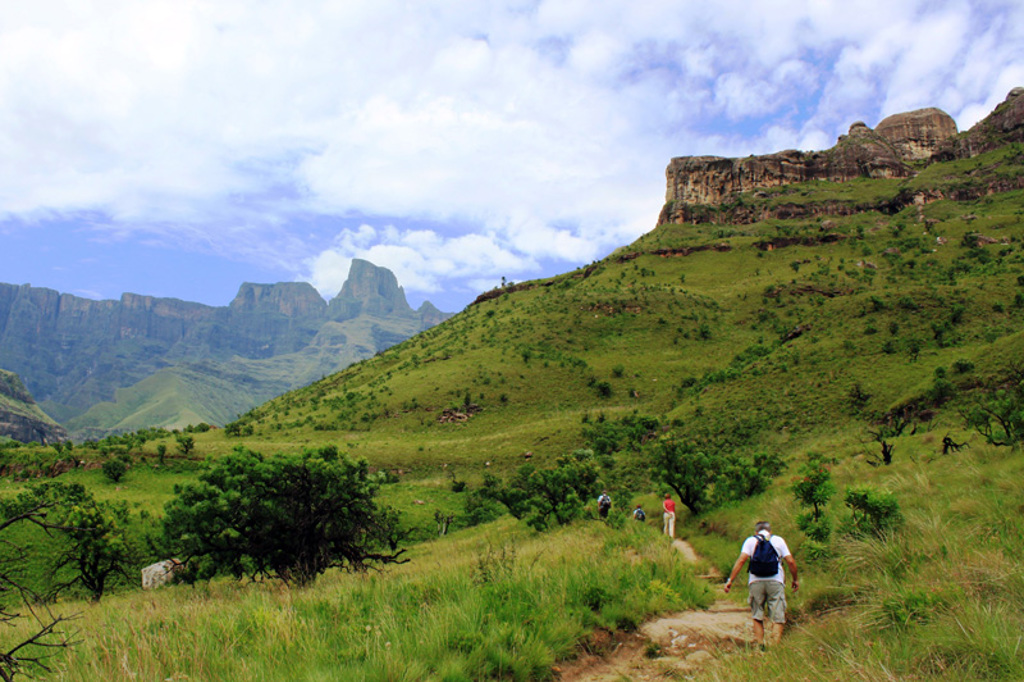 Wandelaars op bergpad door groen heuvel- en berglandschap tijdens groepsrondreis Zuid-Afrika kampeerreis.