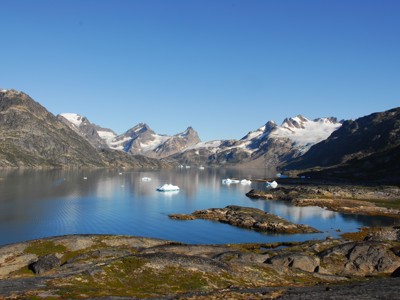 Uitzicht over de fjord bij Disko Bay in Groenland, met drijvende ijsbergen en besneeuwde bergtoppen.