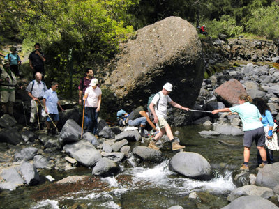 Wandelaars steken een beek over via rotsen tijdens de 10-daagse wandelvakantie Tenerife & La Palma.