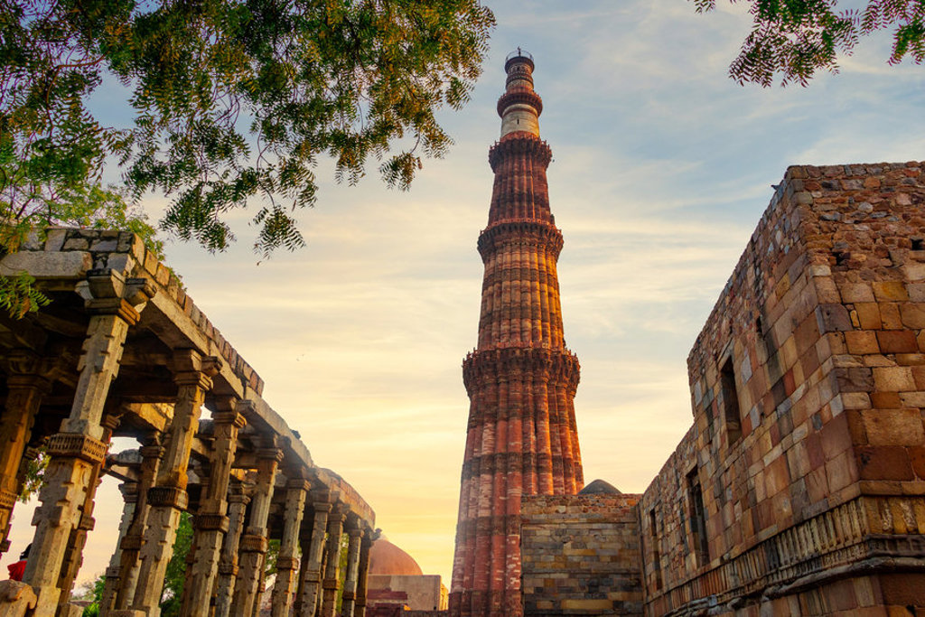 Qutub Minar in Delhi bij zonsondergang, een hoog roodstenen minaretcomplex tijdens een 22-35ers reis India.