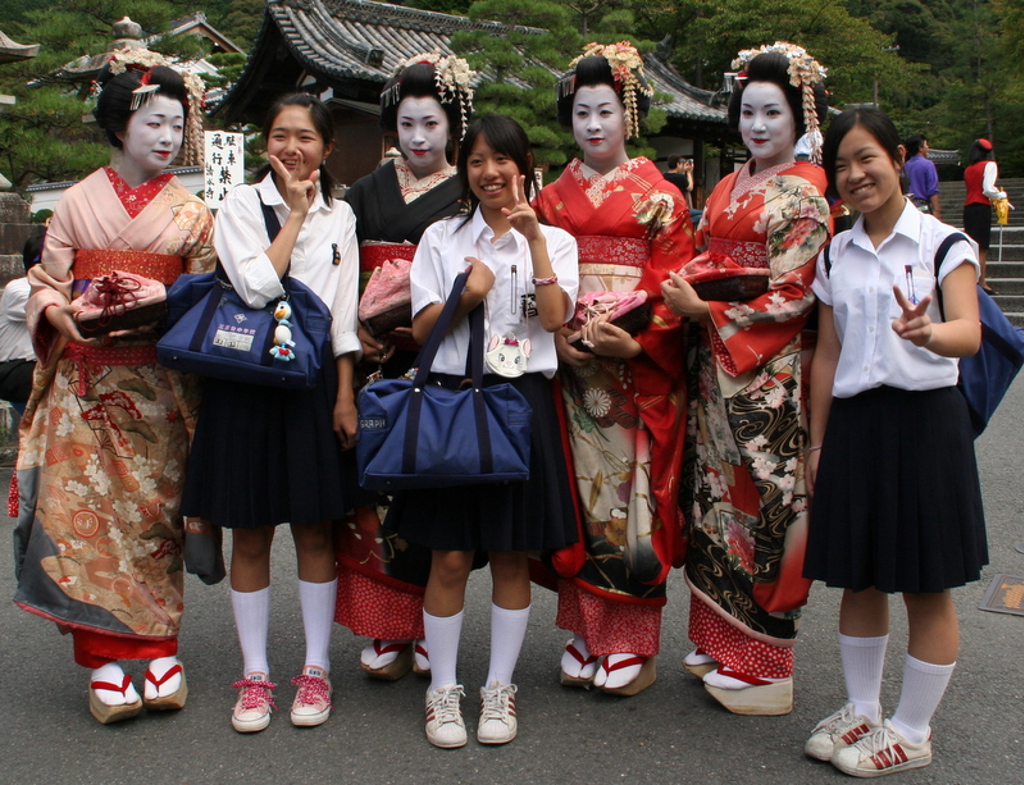 Japanse geisha’s in kleurrijke kimono’s poseren met schoolmeisjes tijdens een familiereis Japan.