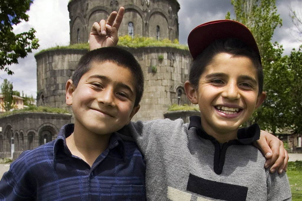 Twee lachende jongens voor een historische stenen kerk tijdens de groepsrondreis Turkije Hoogtepunten.