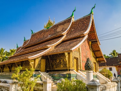 Gouden boeddhistische tempel in Luang Prabang, Laos, met sierlijk dak en mozaïekdecoraties.