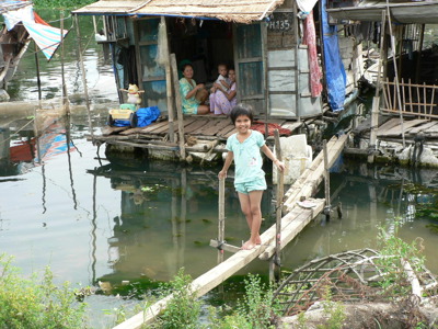 Meisje op een houten loopbrug bij drijvende huizen in de Mekongdelta, Vietnam.