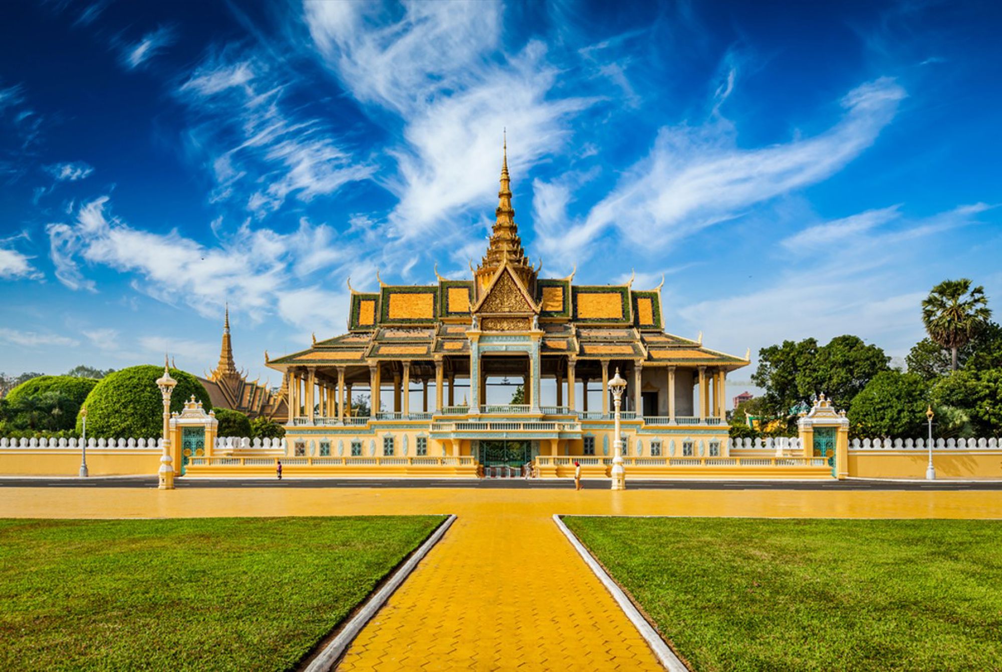 Koninklijk Paleis in Phnom Penh, Cambodja, met gouden daken en een brede laan onder blauwe lucht.