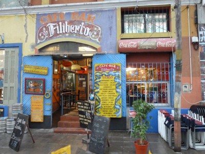 Gevel van café-bar Filiberto met open blauwe deuren, menuborden en terrasstoelen.