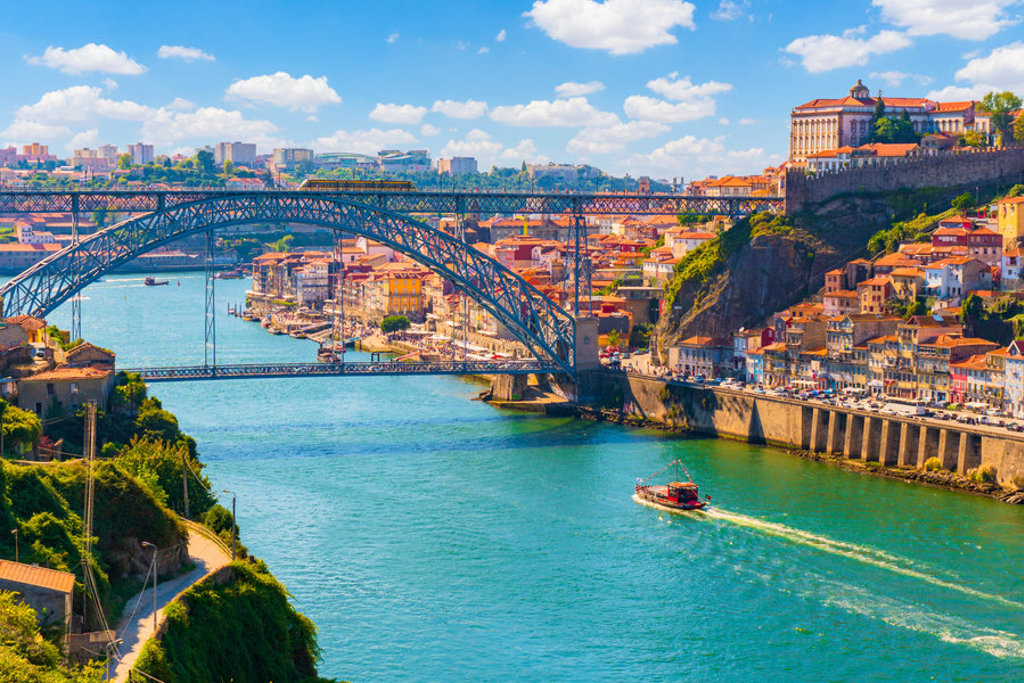 Uitzicht op de Dom Luís I-brug over de Douro in Porto, Portugal, met kleurrijke huizen langs de rivier.