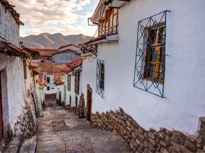 Steeg met stenen trappen en witgekalkte huizen in Cusco, Peru, met uitzicht op de Andes.