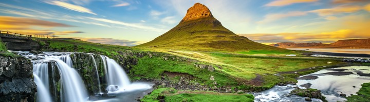 Kirkjufell-berg bij Grundarfjörður op IJsland, met Kirkjufellsfoss-waterval en groene heuvels.