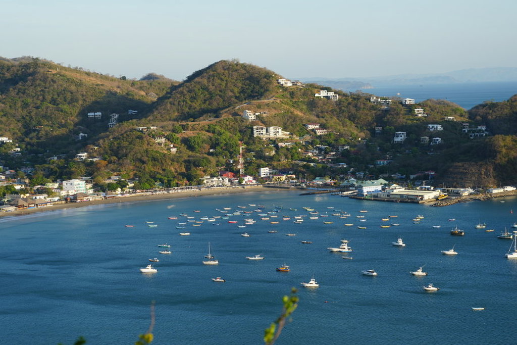 Uitzicht op de baai van San Juan del Sur met boten voor de kust en heuvels op de achtergrond.