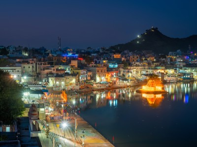Avondzicht op Pushkar Lake met verlichte ghats en stad, Rajasthan, tijdens de route India.