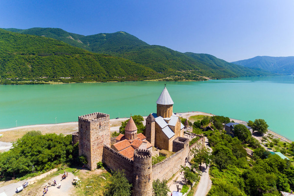 Ananuri-fort en kerk aan het Zjinvali-stuwmeer in Georgië, met groene bergen op de achtergrond.