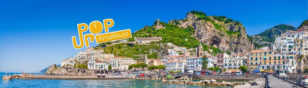 Panorama van Amalfi aan de Amalfikust met kleurrijke huizen tegen de rotsen en de zee op de voorgrond.