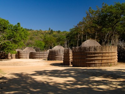 Traditioneel Zulu-dorp met ronde rieten hutten en houten omheining in het groen van Zuid-Afrika.