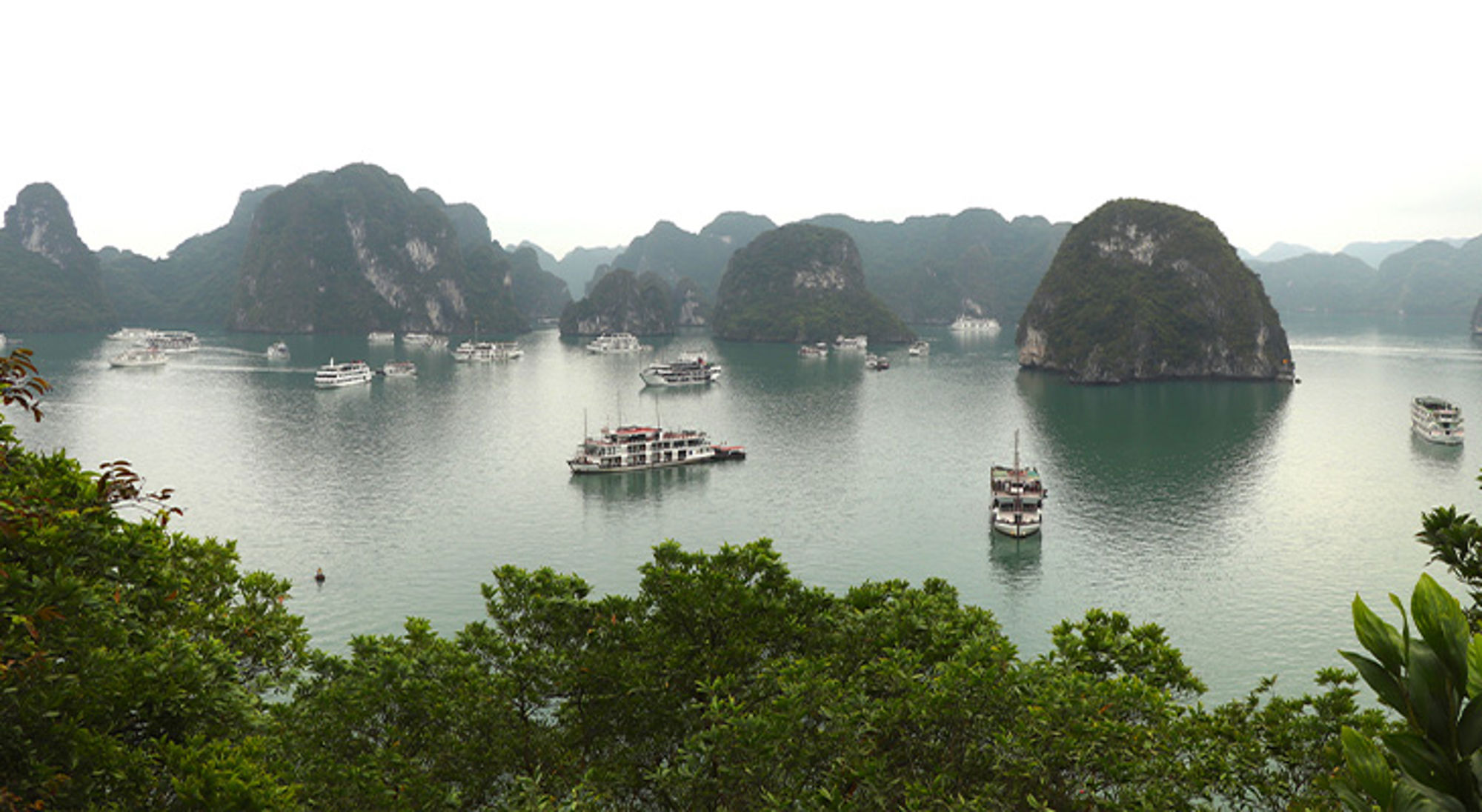 Halong Bay Uitzicht over Halong Bay met kalkstenen rotsformaties en rondvaartboten op het rustige water.