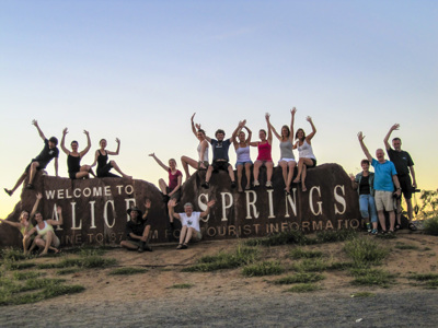 Groepsfoto bij het Welcome to Alice Springs-bord in Australië.