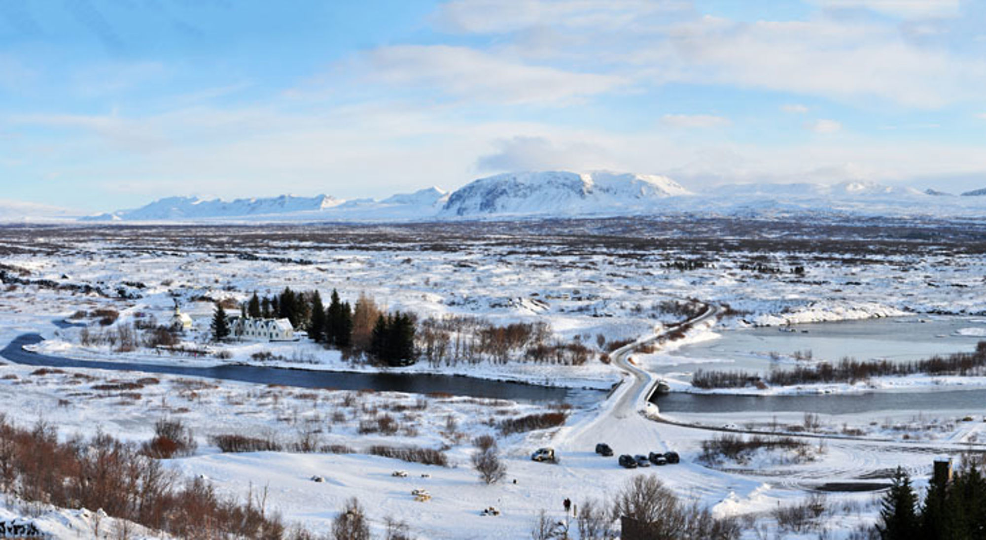 Thingvellir winter IJsland Sneeuwlandschap in IJsland met rivier, brug en bergen op de achtergrond.