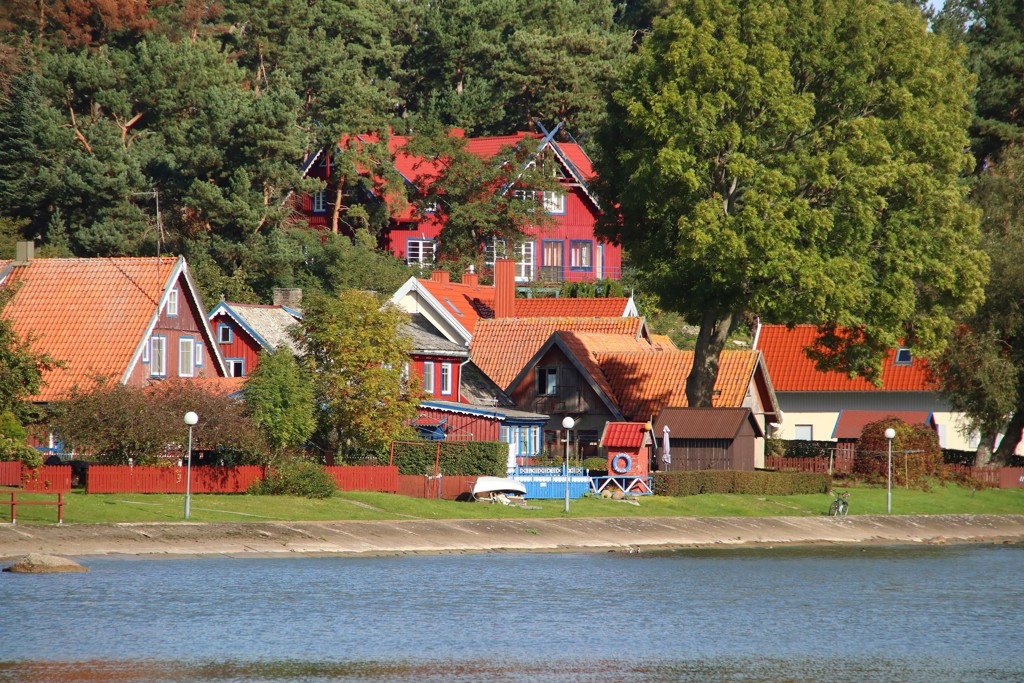 Kleurrijke houten huizen met rode daken aan het water tijdens familiereis Polen en Baltische Staten.