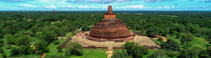 Ruwanwelisaya-stoepa in Anuradhapura, omringd door groen onder een blauwe lucht.