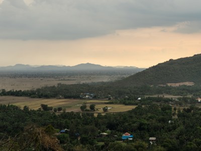 Uitzicht over rijstvelden en heuvels in Cambodja bij zonsondergang.