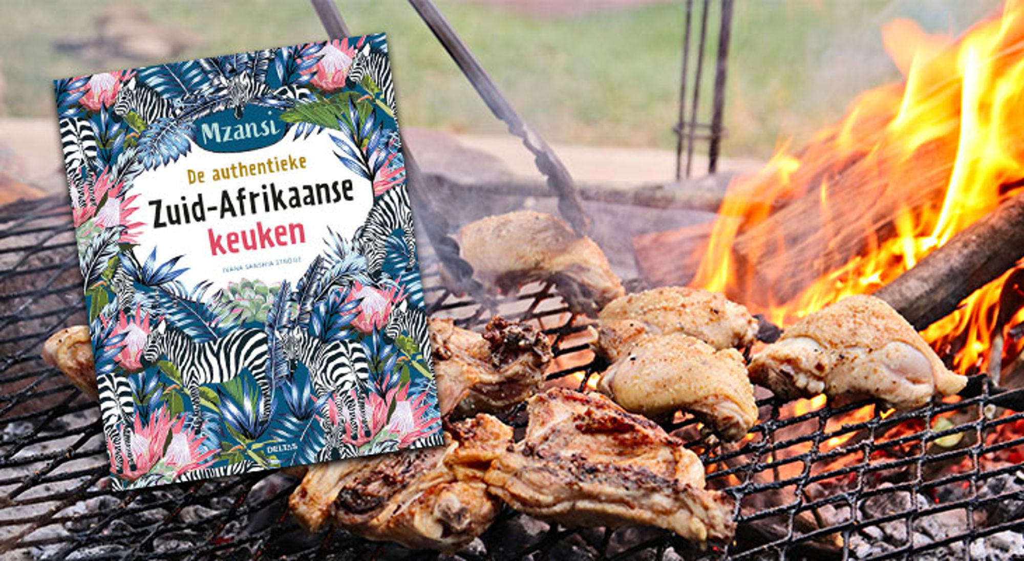 Kookboek “De authentieke Zuid-Afrikaanse keuken” naast gegrilde kip op een braai boven open vuur.