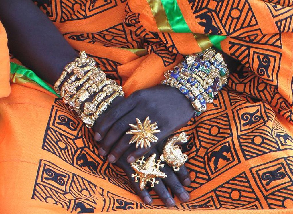 Handen met sieraden op kleurrijke stof tijdens groepsrondreis Ghana, Togo en Benin.