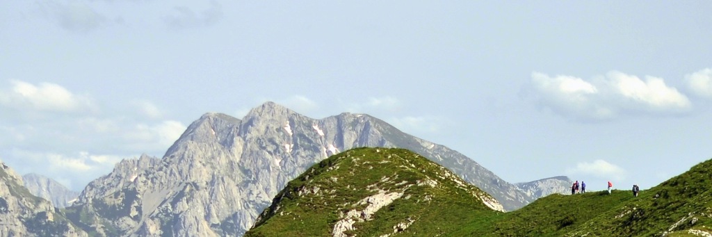 Wandelaars op een groene bergkam met ruige bergtoppen op de achtergrond in Bosnië en Herzegovina.