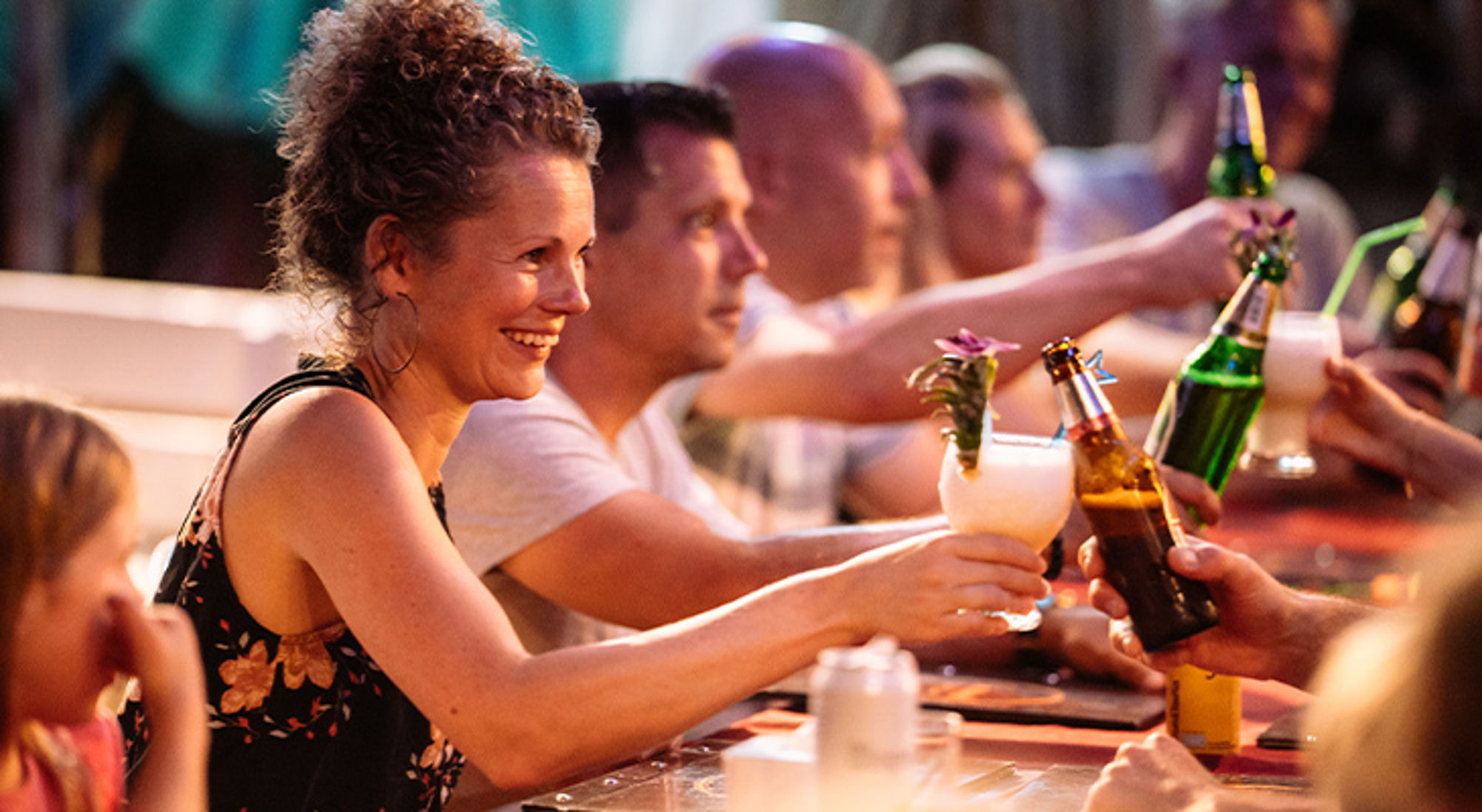 Ouders familiereis Vrienden proosten met bier en cocktails op een terras tijdens een zomerse avond.