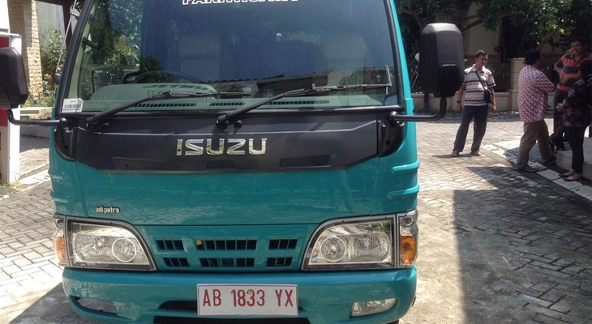 Turquoise Isuzu-busje met kenteken AB 1833 YX op straat in Indonesië.
