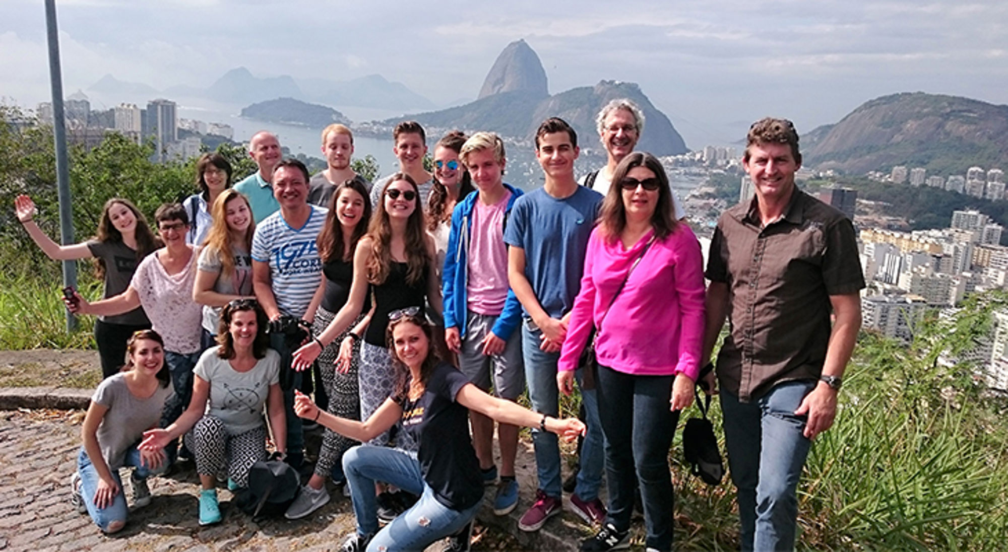 Groepsfoto van reizigers bij een uitzichtpunt in Rio de Janeiro, met de Suikerbroodberg op de achtergrond.