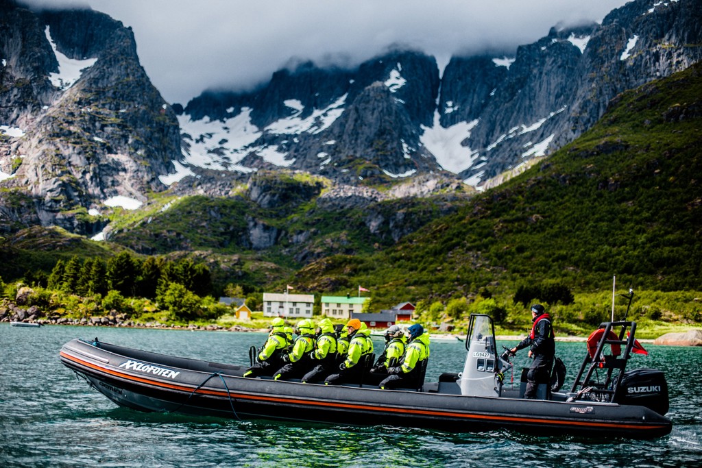 Zodiacboot met reizigers op fjord in Noorwegen, met besneeuwde bergen op de achtergrond.
